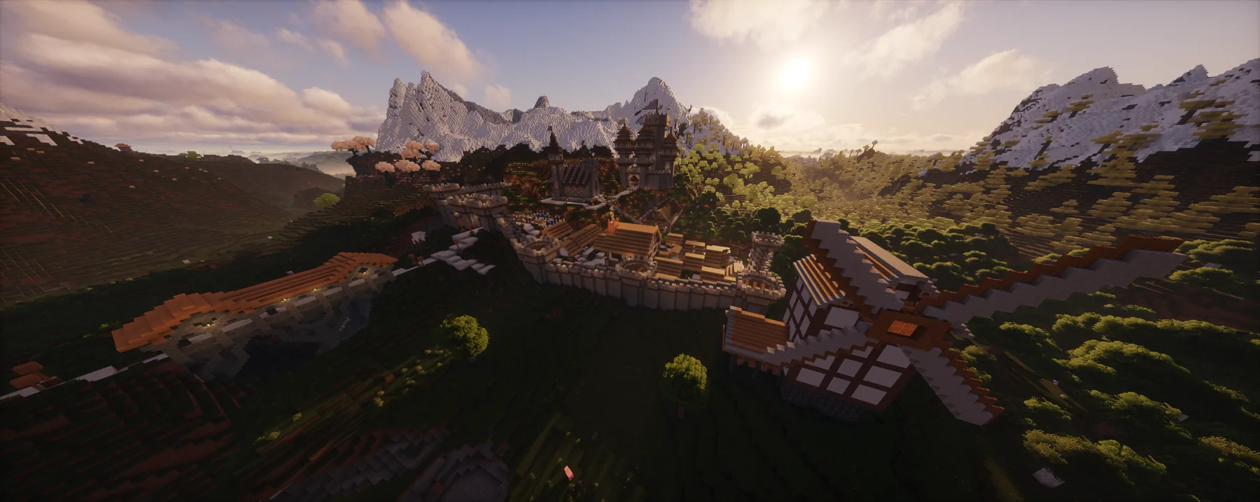 Wide view of the TrainDontStop Minecraft world at sunset with mountains, walls, and rooftops.